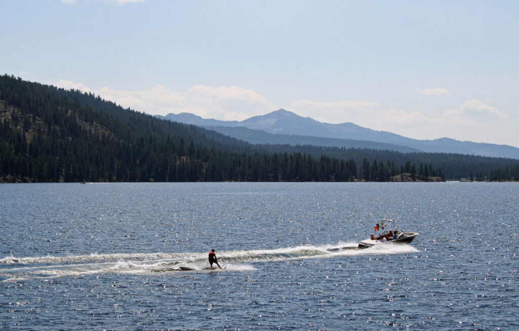 Boat pulling either a waterskier or wakeboarder on Payette Lake in McCall, Idaho.